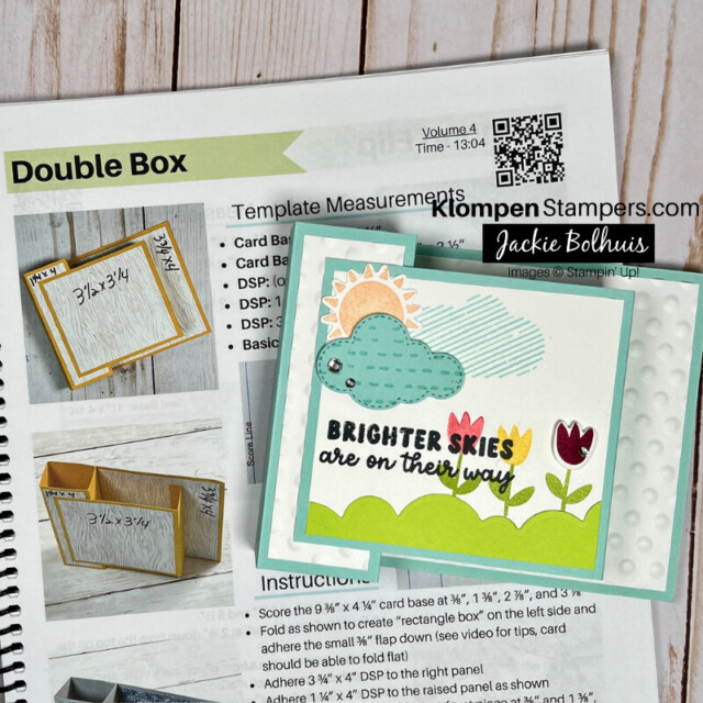 A double box fun fold card that has an outdoor scene with tulips, grass, sun, and cloud. The card is lying on top of an instruction sheet on how to make the fun fold.